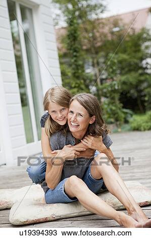 Mother and daughter hugging on patio View Large Photo Image Stock Image - Mother and daughter hugging on patio. Fotosearch
