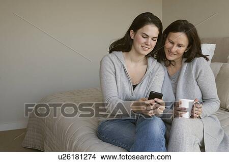Picture - Mother and daughter looking at phone. Fotosearch
