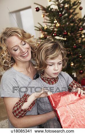Stock Image - Mother and daughter opening gift. Fotosearch