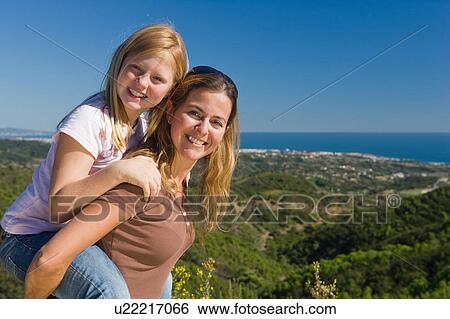 Stock Photograph - Mother and daughter piggyback ride. Fotosearch