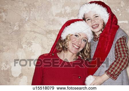 Stock Photo - Mother and daughter wearing Santa hats. Fotosearch