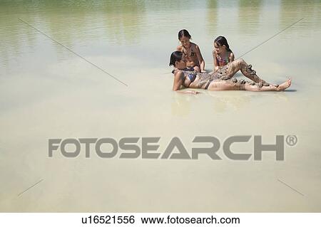 Stock Photograph - Mother and daughters play in a lake. Fotosearch