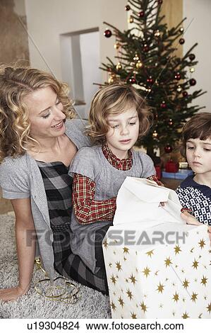 Mother and kids opening gift View Large Photo Image Picture - Mother and kids opening gift. Fotosearch