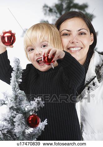 Stock Photo - Mother and son decorating a snowytree. Fotosearch