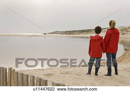 Stock Image - Mother and son looking out on beach. Fotosearch