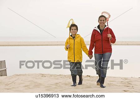 Stock Image - Mother and son on beach with fishing net. Fotosearch