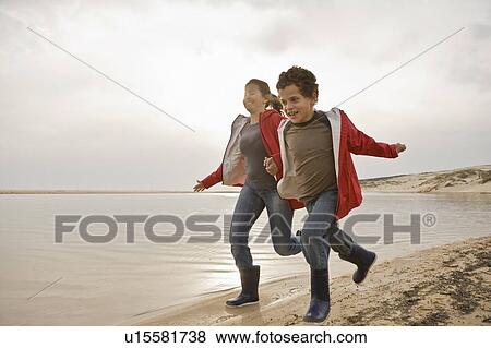 Stock Photo - Mother and son running together on beach. Fotosearch