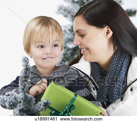 Mother and son with present by the tree View Large Photo Image Stock Image - Mother and son with present by the tree. Fotosearch