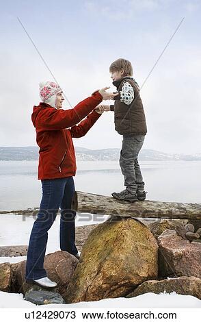 Stock Image - Mother helping son balancing. Fotosearch