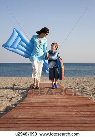 Mother & son walking on beach with lilo View Large Photo Image Stock Image - Mother & son walking on beach with lilo. Fotosearch