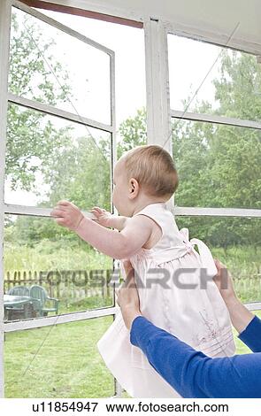 Mum holding baby at the window View Large Photo Image Stock Photo - Mum holding baby at the window. Fotosearch