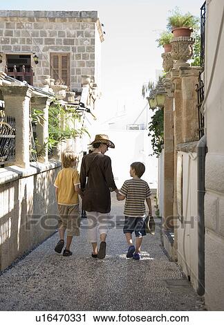 Stock Image - Mum walking with two sons. Fotosearch