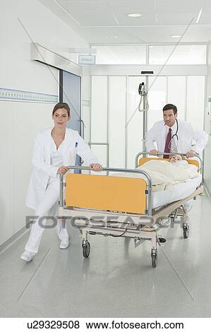 Nurse and doctor pushing bed in hall View Large Photo Image Stock Photo - Nurse and doctor pushing bed in hall. Fotosearch