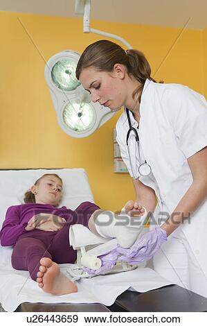 Nurse applying a dressing at girls foot View Large Photo Image Stock Photo - Nurse applying a dressing at girls foot. Fotosearch