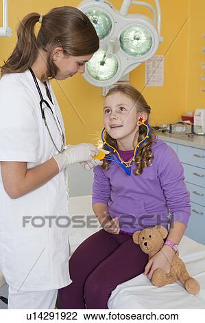Stock Image - Nurse explaining girl stethoscope. Fotosearch