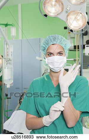 Nurse in scrubs putting on gloves View Large Photo Image Stock Image - Nurse in scrubs putting on gloves. Fotosearch