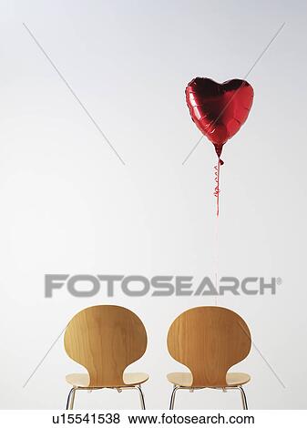 Stock Photo - Office Chairs and love heart balloon. Fotosearch