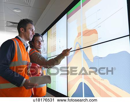 Stock Image - Oil workers with geology screen. Fotosearch