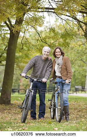 Older man and woman cycle in the park View Large Photo Image Stock Photograph - Older man and woman cycle in the park. Fotosearch
