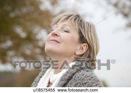 Stock Photography - Older woman relaxing outdoors in autumn. Fotosearch
