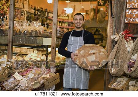 Stock Image - Owner in front of deli. Fotosearch