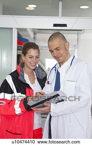 Stock Image - Paramedic and doctor examining file. Fotosearch