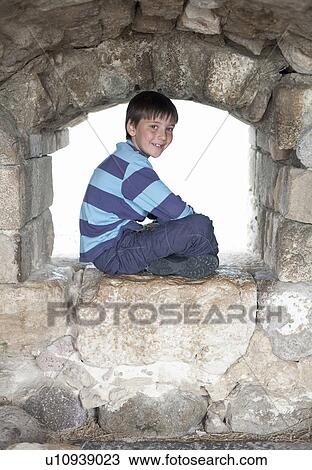 Portrait of boy sitting on old wall View Large Photo Image Stock Image - Portrait of boy sitting on old wall. Fotosearch