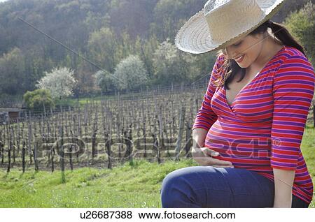 Stock Photo - Pretty pregnant woman in straw hat. Fotosearch