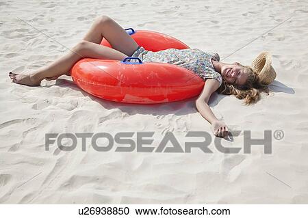 Stock Image - Pretty woman lying on the sand smiling. Fotosearch
