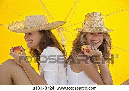 Picture - Pretty women eating fruit in the shade. Fotosearch