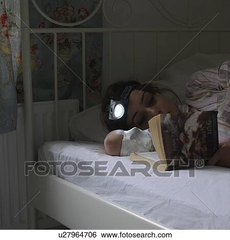 Stock Photograph - Reading book with head torch. Fotosearch