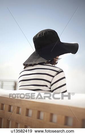 Stock Photo - Rear view of woman in sun hat. Fotosearch