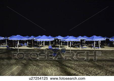 Stock Photography - Row of sun parasols, night time. Fotosearch