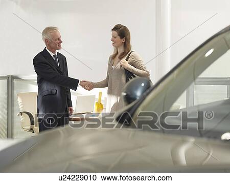Stock Image - Salesman and customer in car dealership. Fotosearch