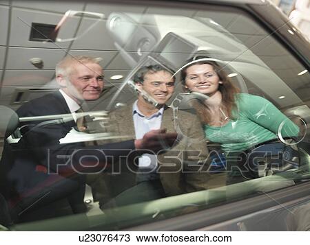 Salesman and customers in car dealership View Large Photo Image Stock Image - Salesman and customers in car dealership. Fotosearch