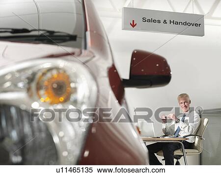 Salesman at desk in car dealership View Large Photo Image Stock Photography - Salesman at desk in car dealership. Fotosearch