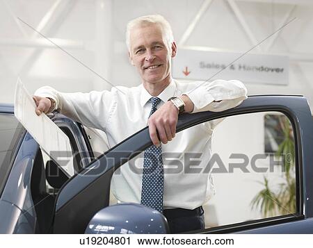 Stock Image - Salesman with car in car dealership. Fotosearch