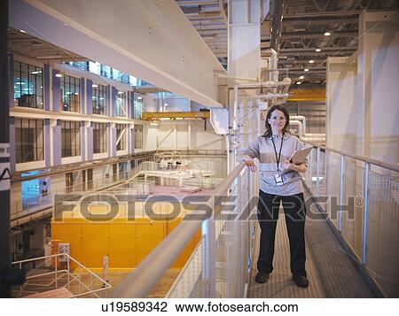 Stock Image - Scientist in particle accelerator hall. Fotosearch