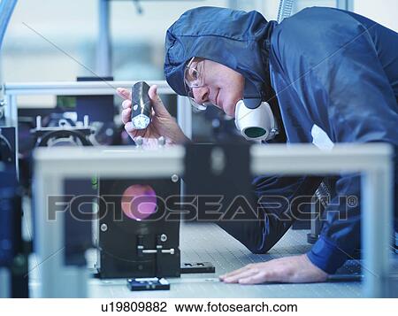 Stock Image - Scientist inspecting laser crystal. Fotosearch