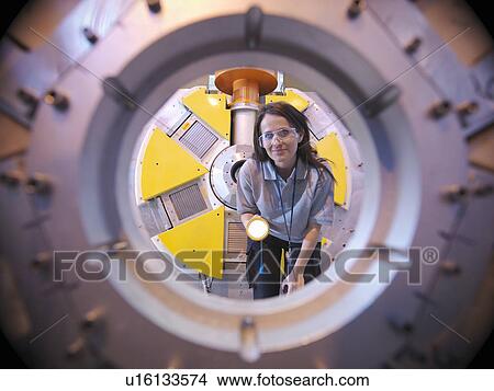 Picture - Scientist inspects particle accelerator. Fotosearch