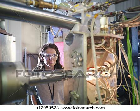 Stock Image - Scientist inspects particle accelerator. Fotosearch
