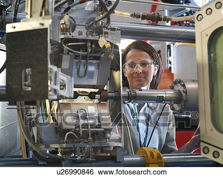Stock Photograph - Scientist inspects particle accelerator. Fotosearch