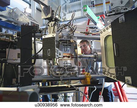 Scientist inspects particle accelerator View Large Photo Image Stock Photograph - Scientist inspects particle accelerator. Fotosearch