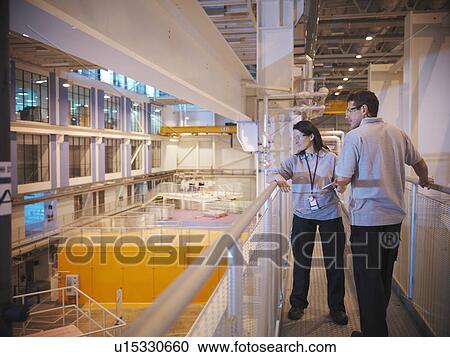 Stock Image - Scientists in particle accelerator hall. Fotosearch