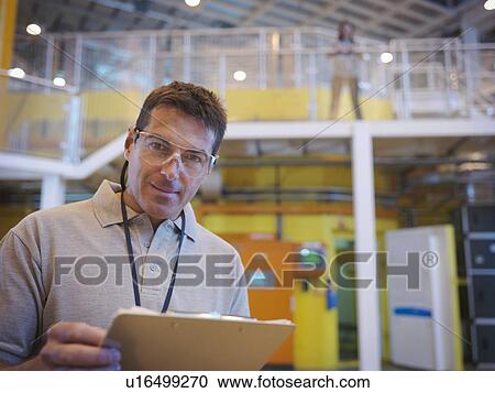 Stock Image - Scientists in particle accelerator hall. Fotosearch