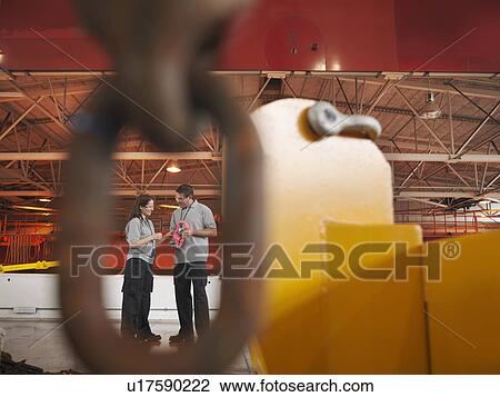 Stock Image - Scientists in particle accelerator hall. Fotosearch