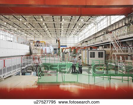 Stock Photography - Scientists in particle accelerator hall. Fotosearch