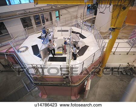 Stock Image - Scientists on particle accelerator. Fotosearch