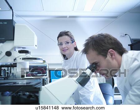 Stock Photo - Scientists using laser microscope. Fotosearch