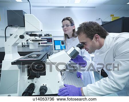 Stock Photograph - Scientists using laser microscope. Fotosearch